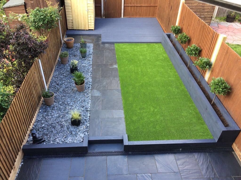Family garden by M&R Property & Paving Services with artificial turf, slate border, grey paving and decking zones