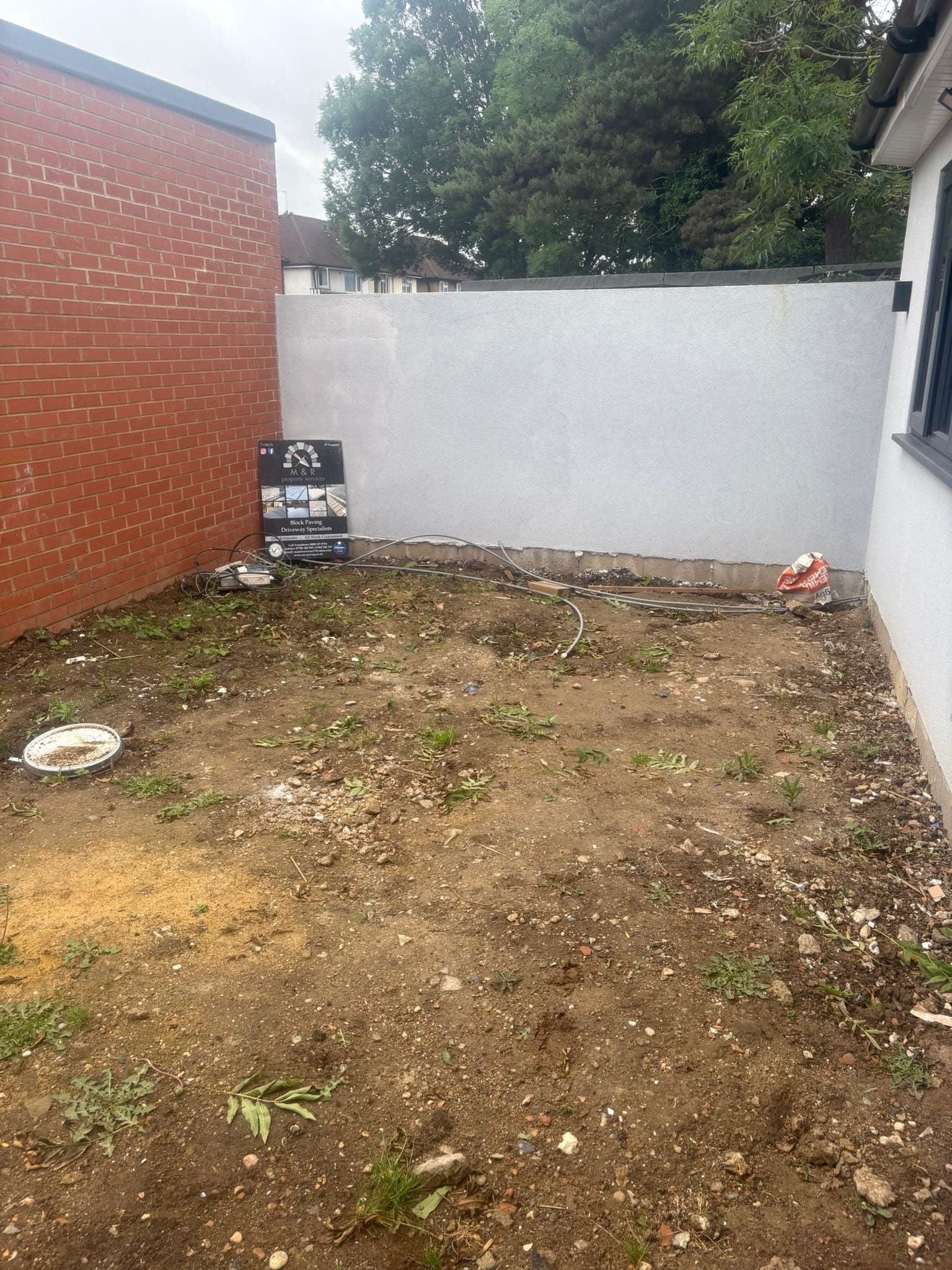 Excavated ground prepared by M&R Property & Paving Services with the company board on site before block paving is laid