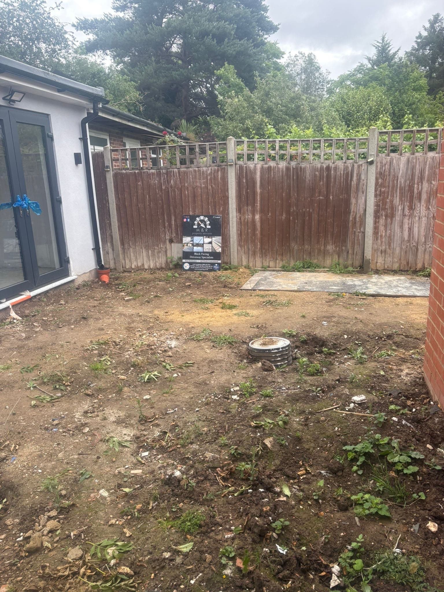 Garden cleared and levelled by M&R Property & Paving Services with the company board on the fence before paving and drainage works